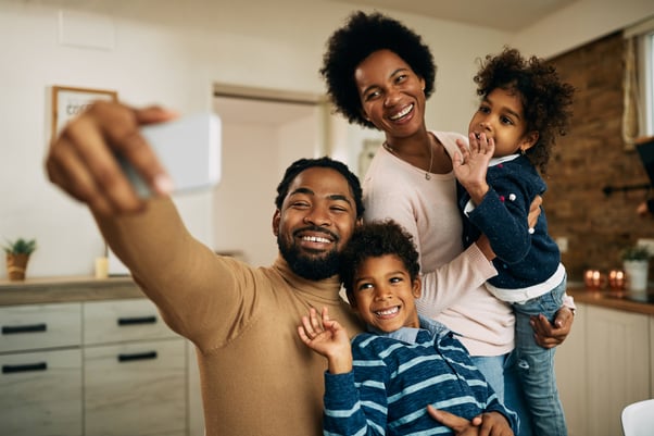 happy-black-parents-with-kids-making-video-call-smart-phone-home